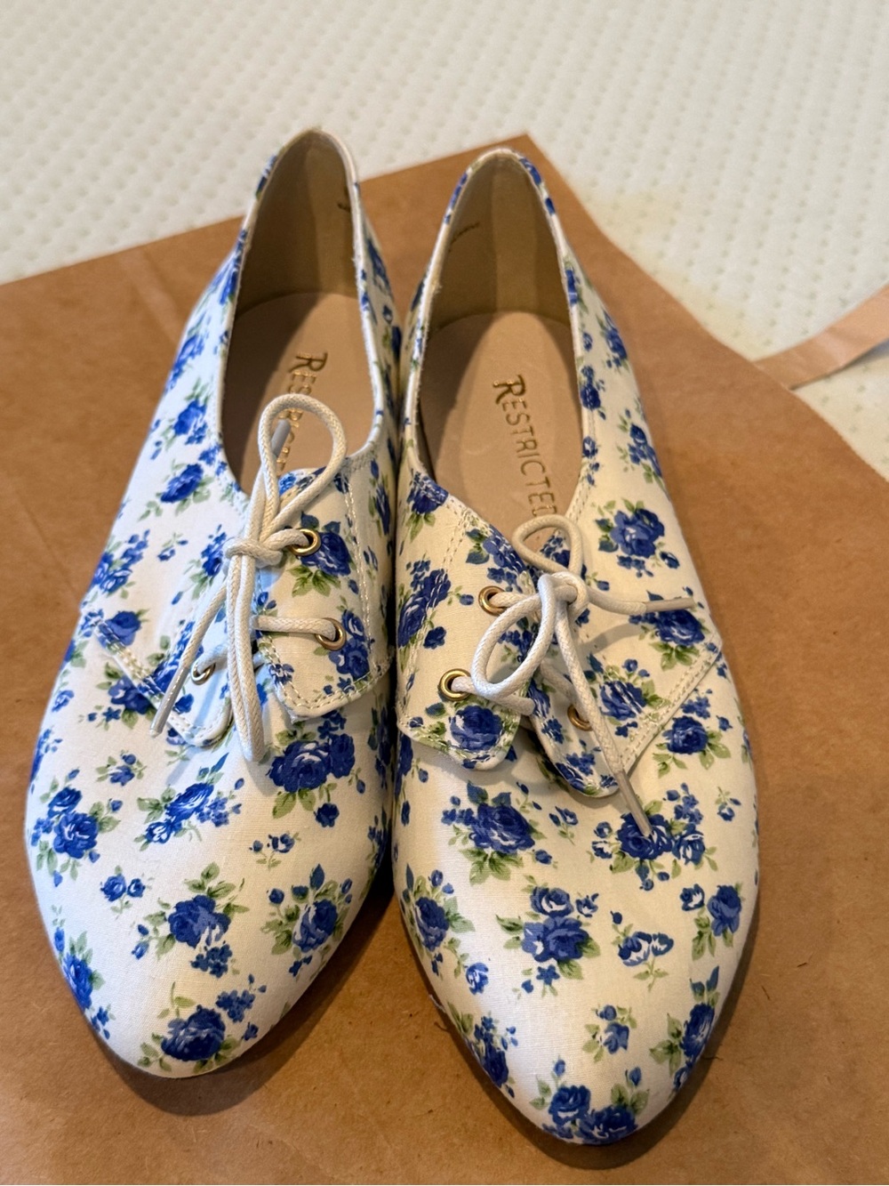 Restricted white floral lace-up flats with blue rose print